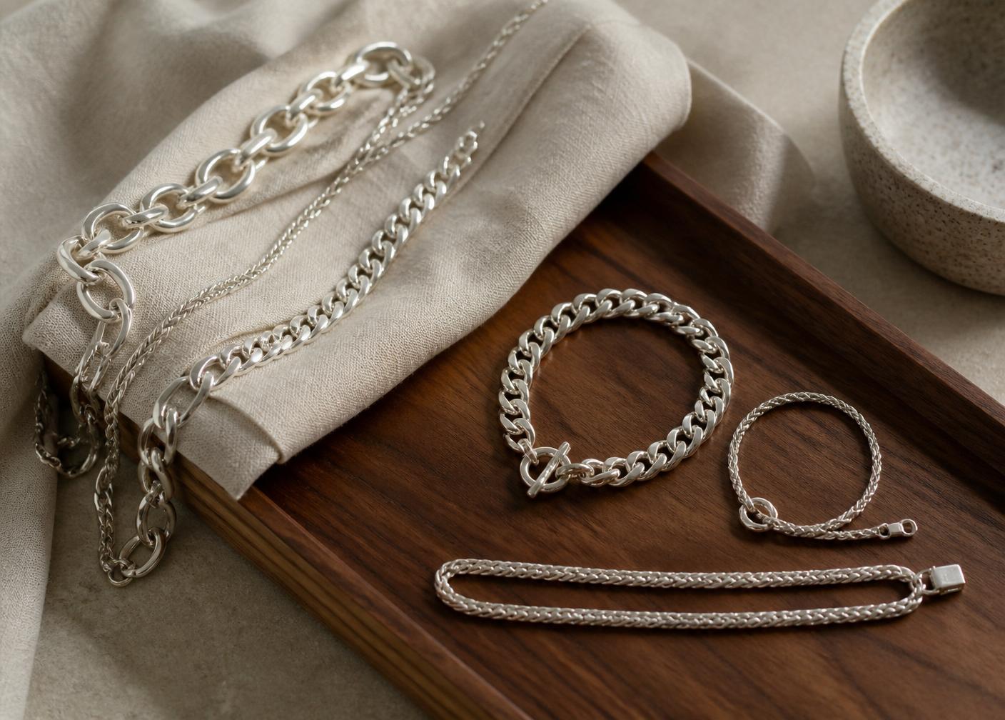 Polished sterling silver chains on walnut and linen